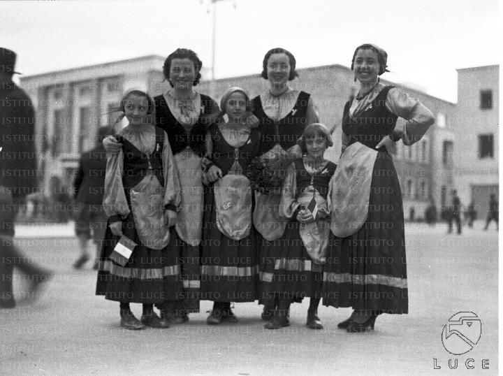 Ragazze e bambine posano in una piazza di Littoria, vestite in abiti tradizionali data 26.04.1936